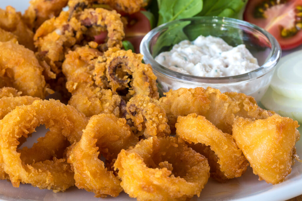 The Perfect Dining Experience - flash fried calamari served on a white plate with a dipping sauce